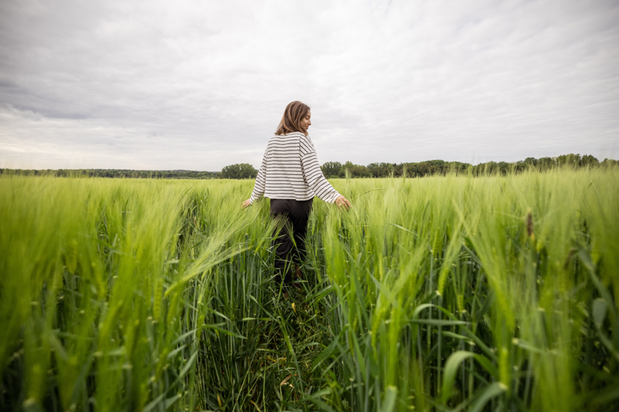 Relaxed woman standing in green field and enjoys calm nature